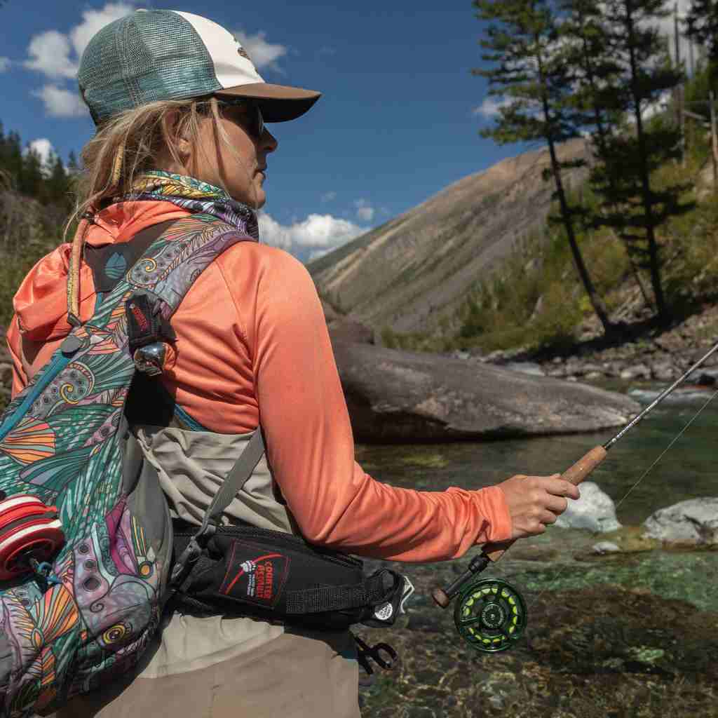 Woman fishing with bear spray in holster on hip.
