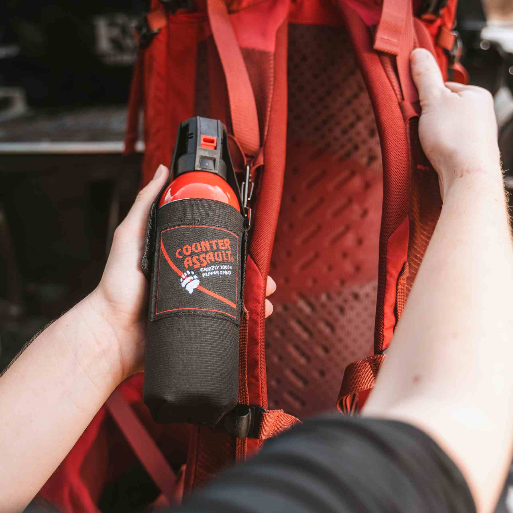 Man with a Counter Assault bear spray attached to bag