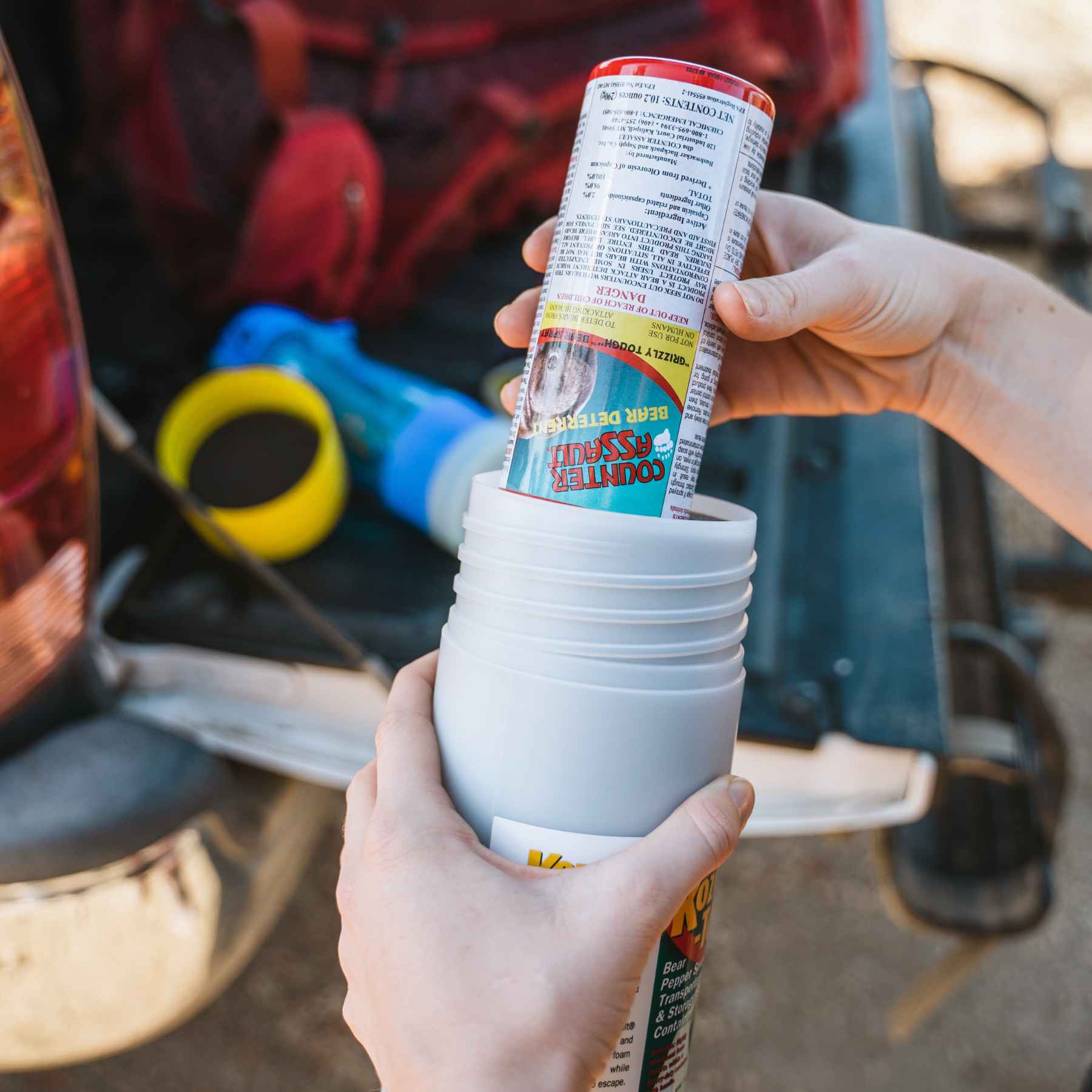 Woman putting bear spray inside the Kozee-Tote spray carrier