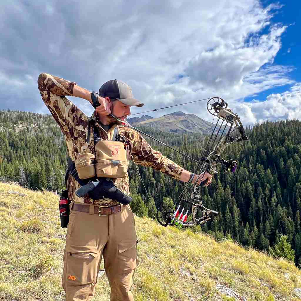 Hunter using bow with bear spray in holster on hip.