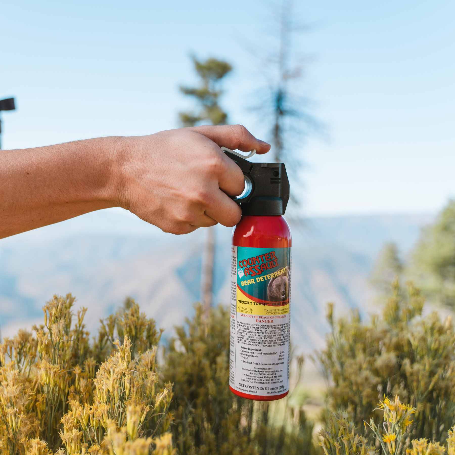 Person holding bear spray in outdoor setting