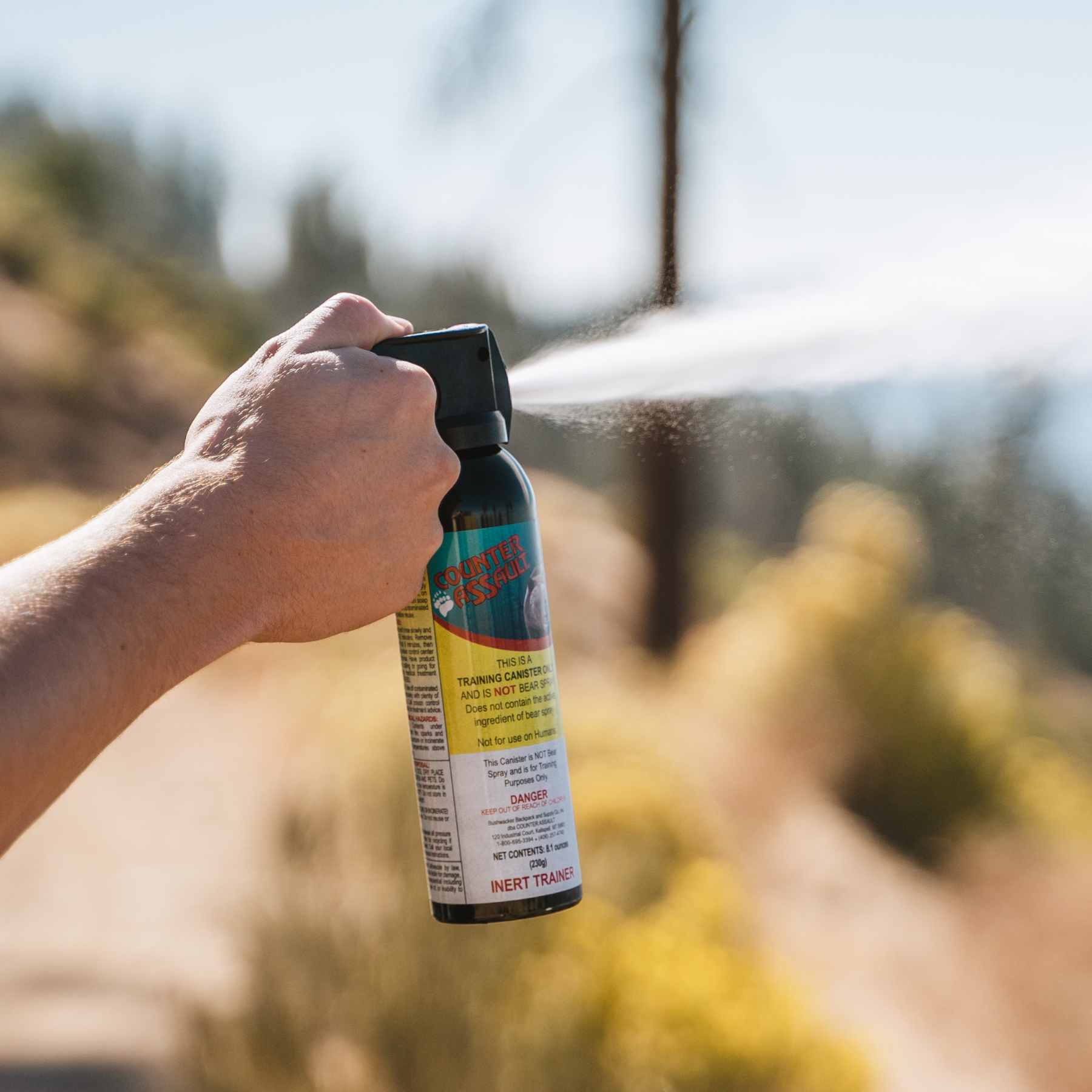 Person spraying inert training canister