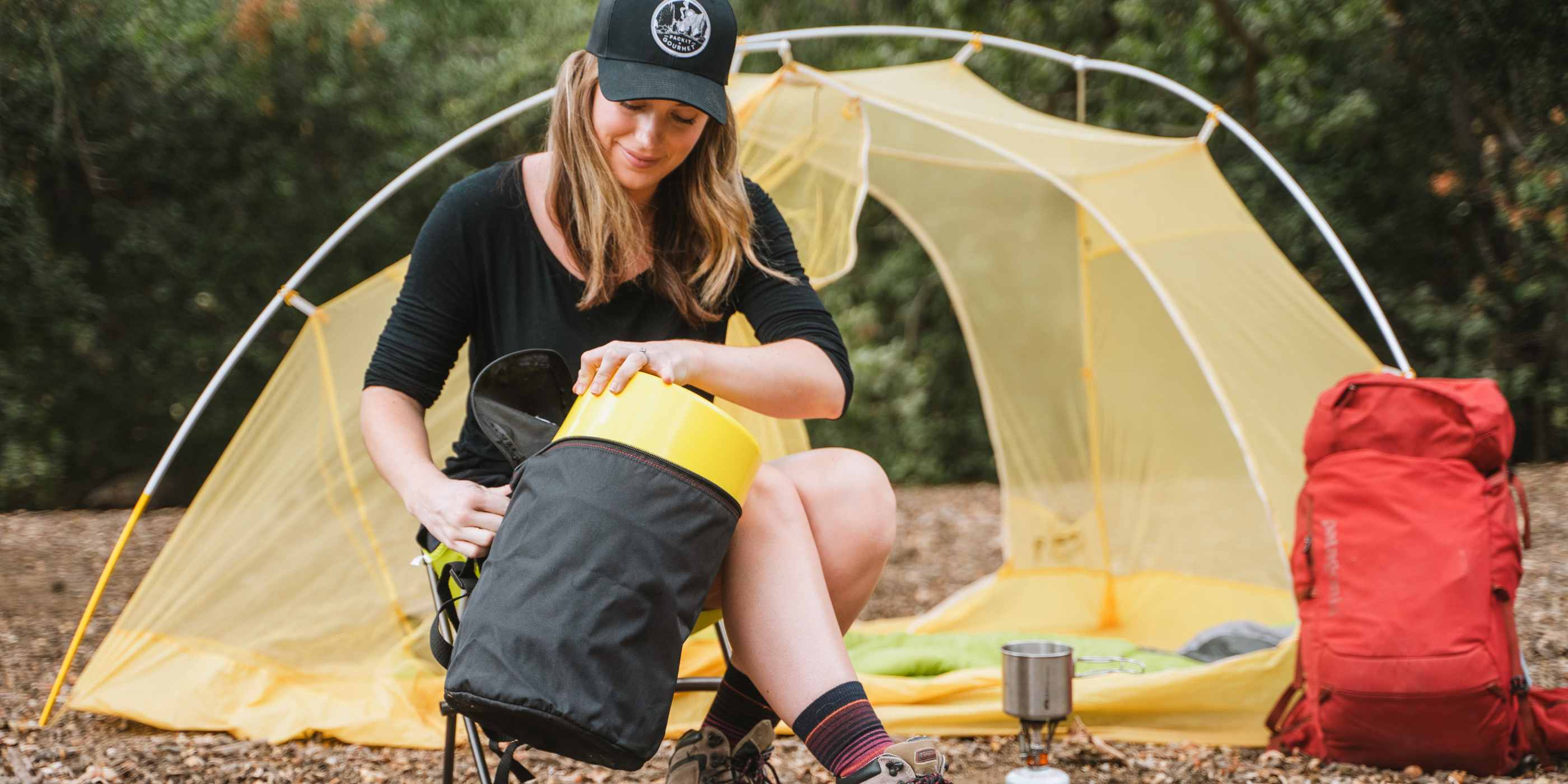 Woman in front of yellow tent pulling yellow Bear Keg out of black carrying case