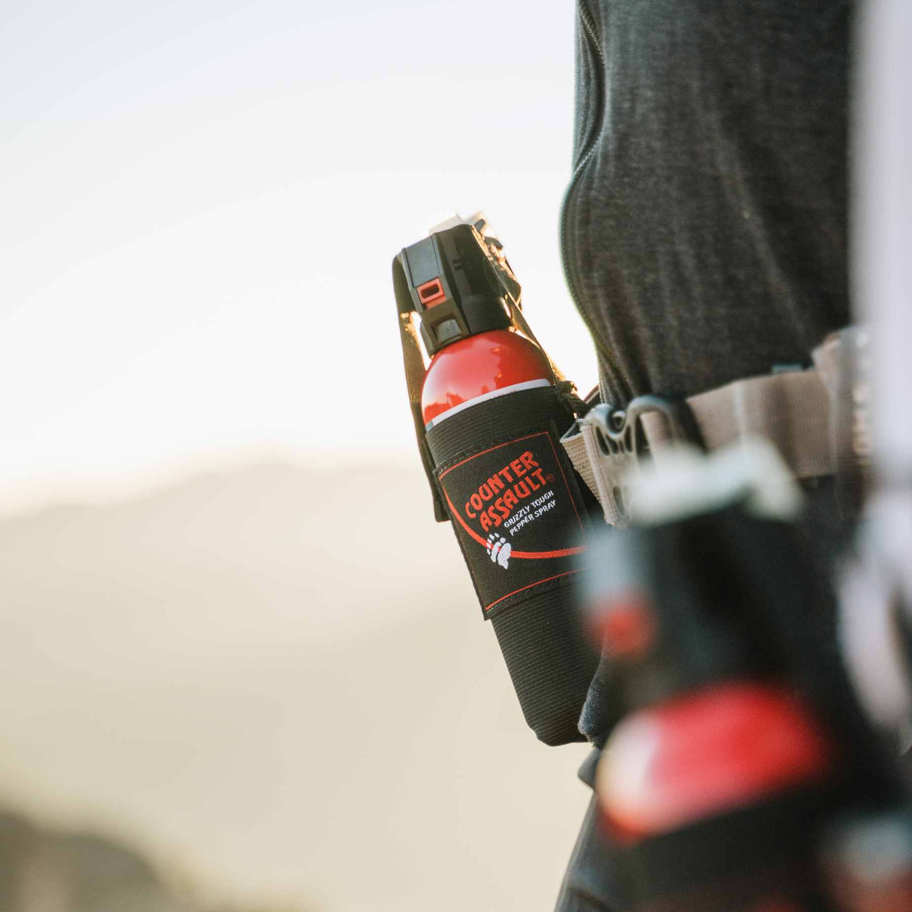 Belt holster with bear spray attached to front of person