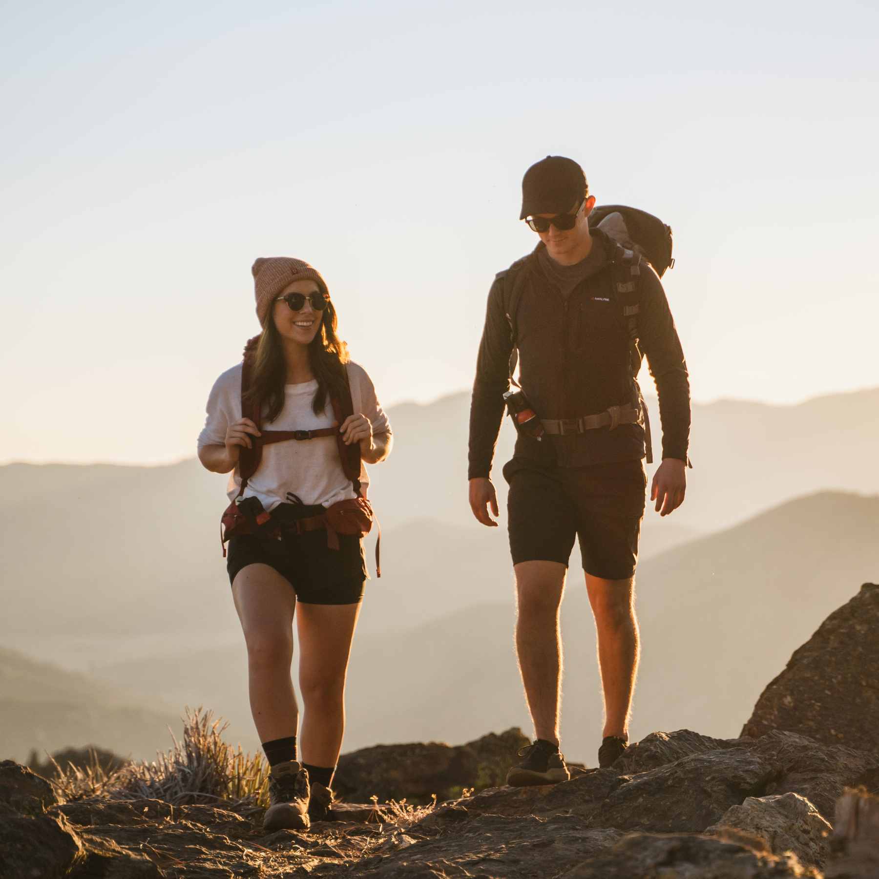 Two hikers with bear spray in front of mountains