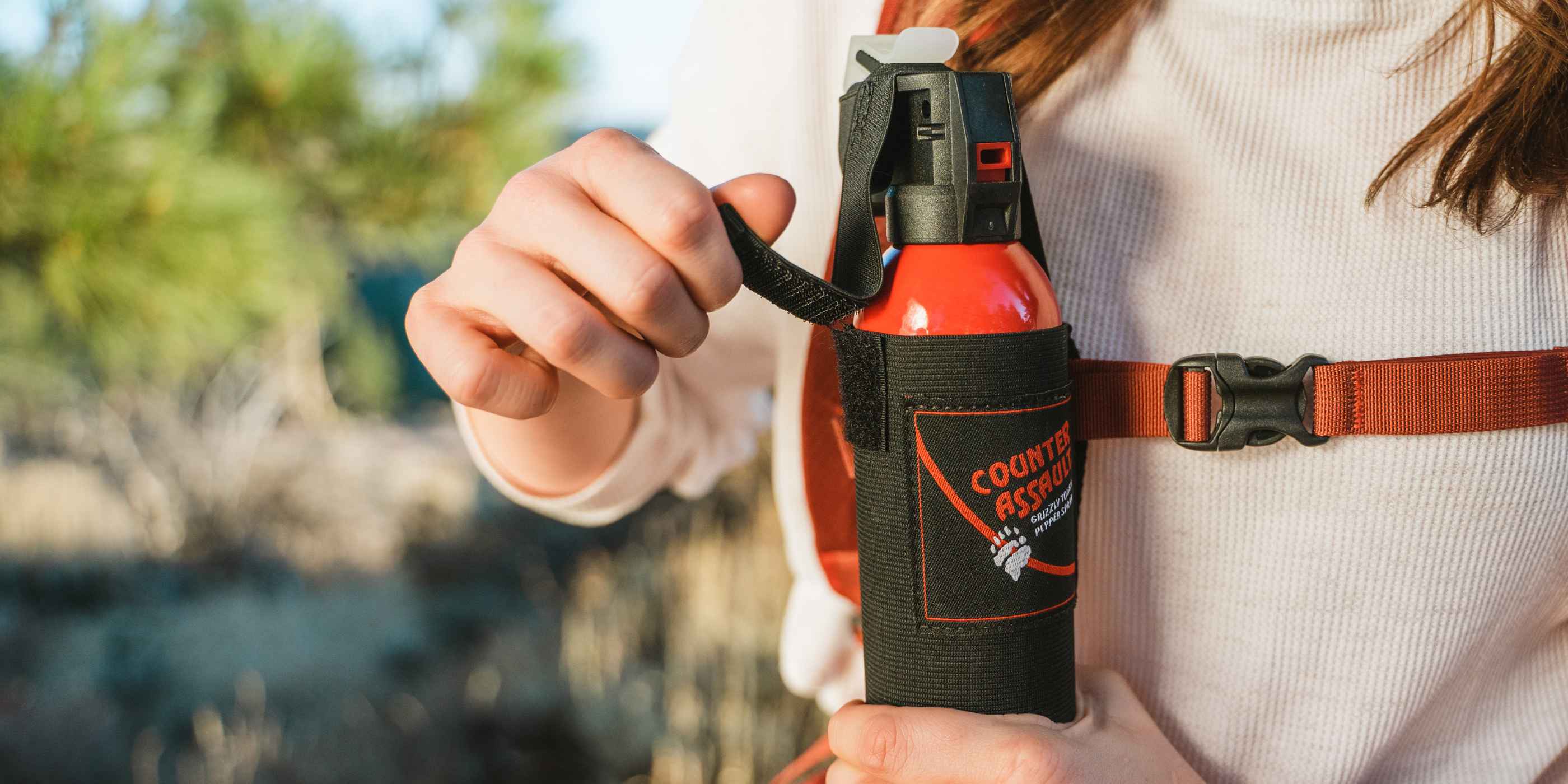 Woman strapping bear spray to chest in a holster