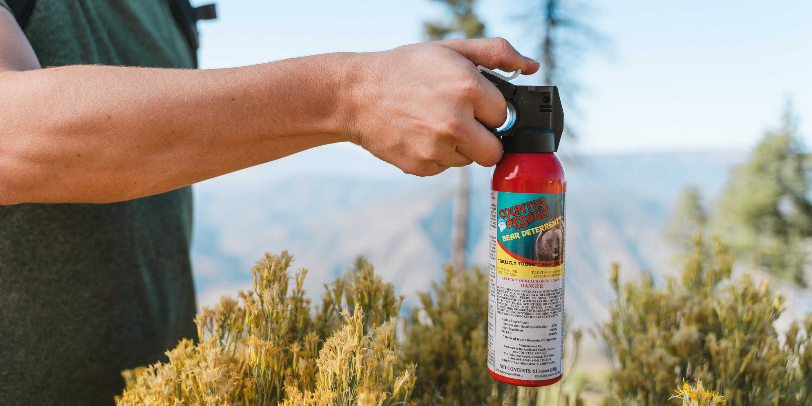 Person holding bear spray in outdoor setting