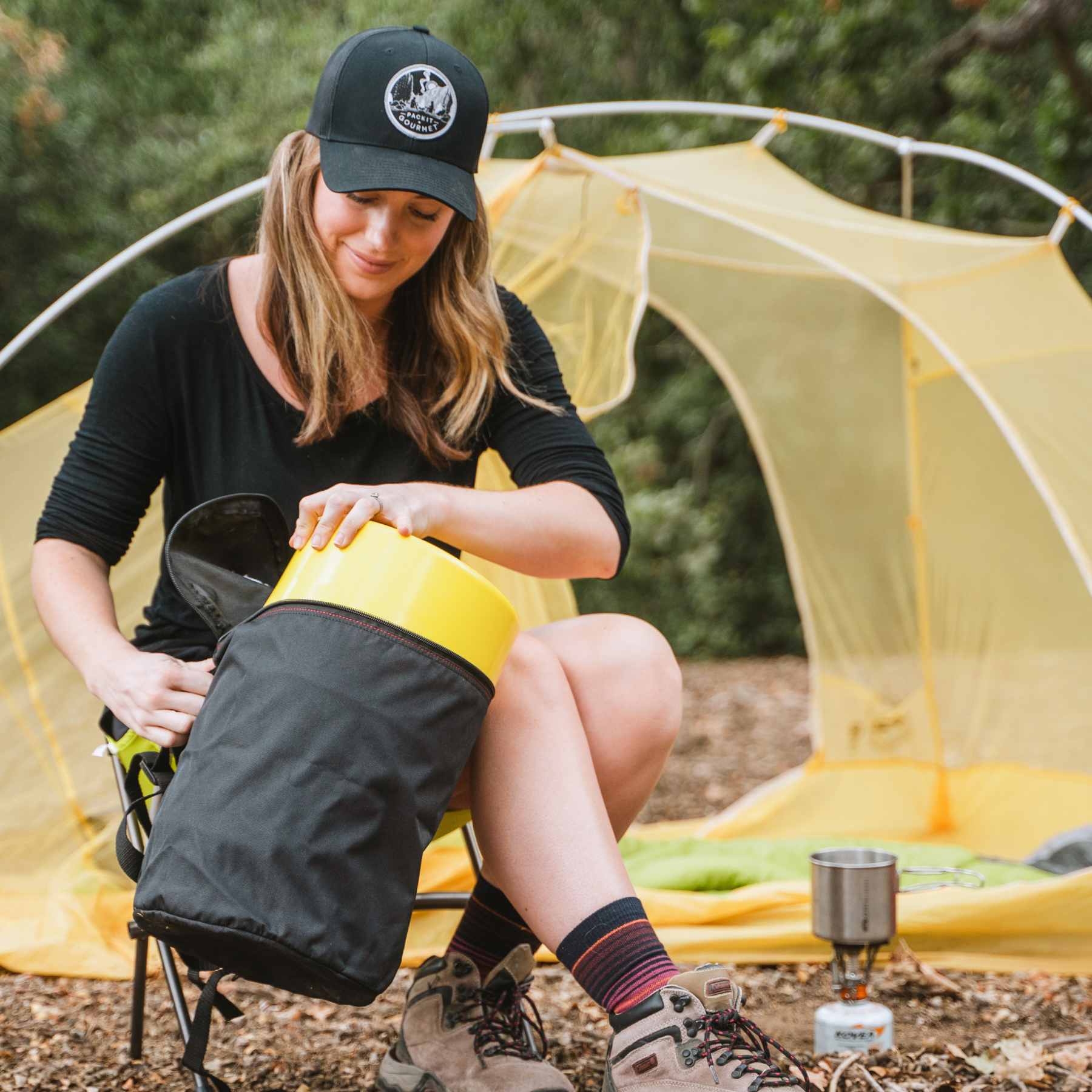 Woman in front of yellow tent pulling yellow Bear Keg out of black carrying case
