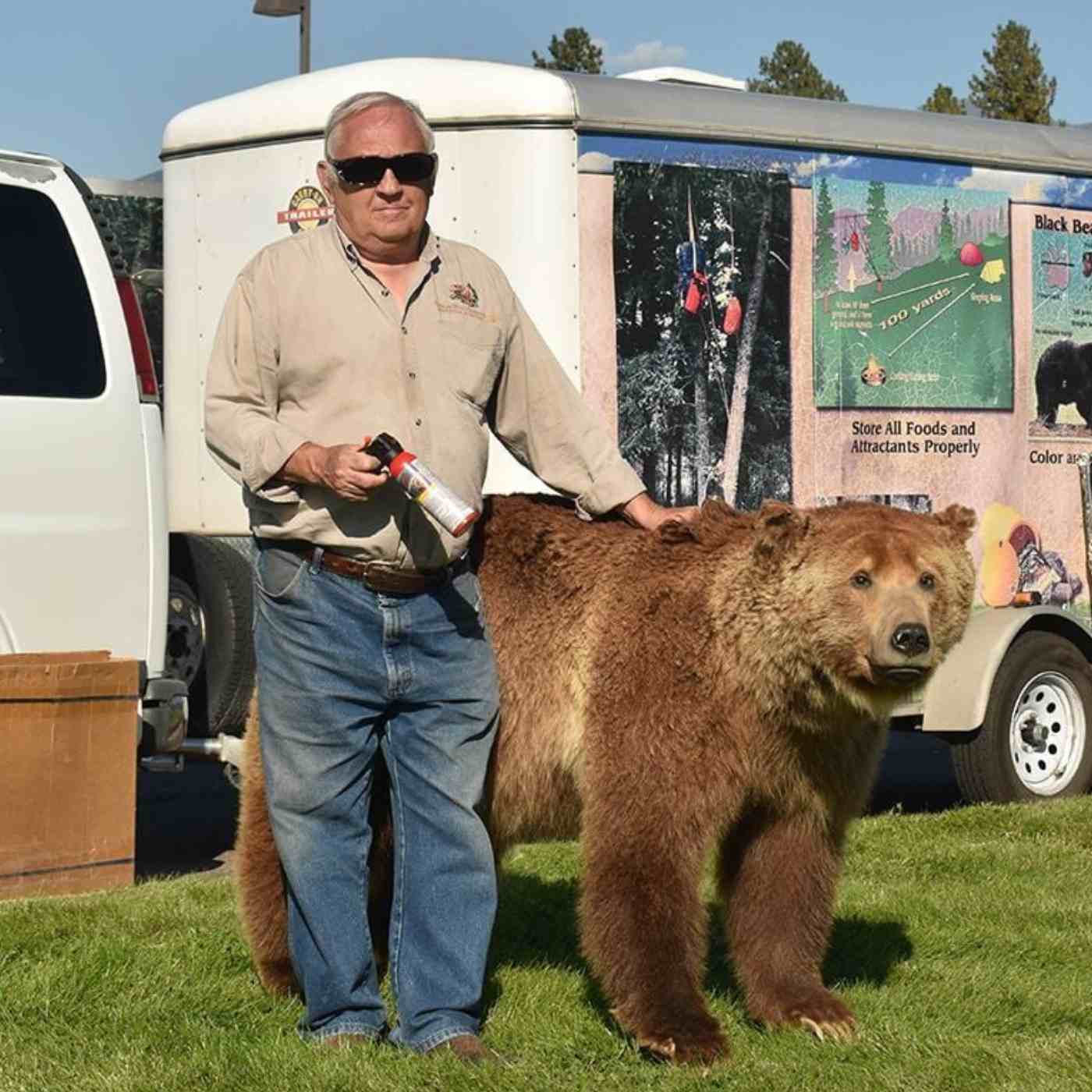 Chuck Bartlebaugh with fake bear in front of truck with trailer